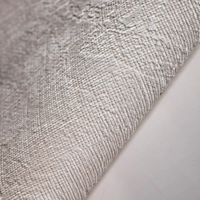 Modern non-woven wallpaper with jute texture and tropical leaf pattern in light beige and cream tones